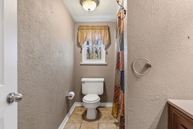 full bath with vanity, toilet, a textured wall, and baseboards