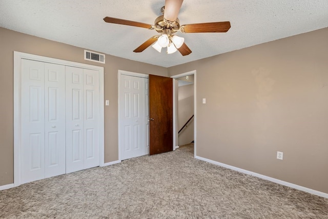 unfurnished bedroom featuring baseboards, visible vents, carpet floors, ceiling fan, and a textured ceiling