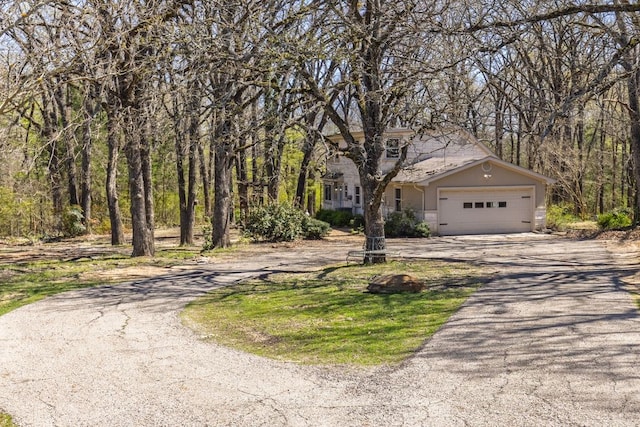 view of property hidden behind natural elements with an attached garage and driveway