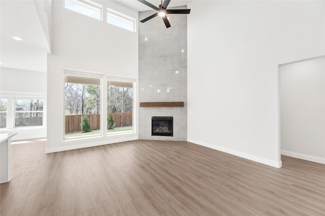 216 Dove Haven Dr, Wylie, TX 75098 - unfurnished living room featuring a towering ceiling, a ceiling fan, wood finished floors, baseboards, and a tile fireplace