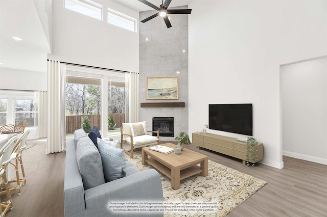 216 Dove Haven Dr, Wylie, TX 75098 - living area with a high ceiling, ceiling fan, a tiled fireplace, wood finished floors, and baseboards