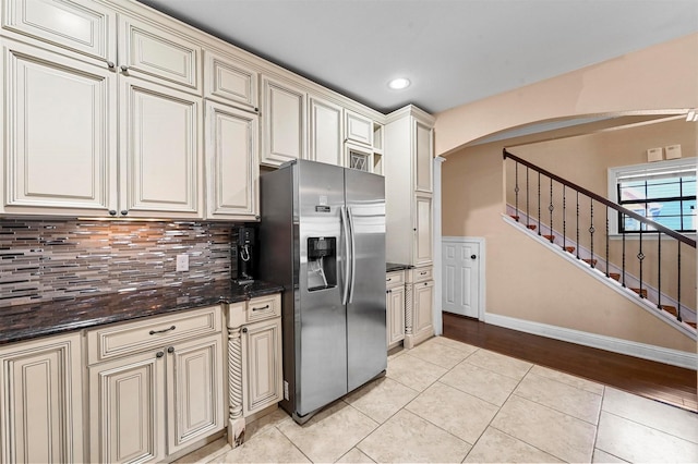 4001 Roswell St, Dallas, TX 75219 - kitchen with stainless steel refrigerator with ice dispenser, cream cabinetry, arched walkways, light tile patterned flooring, and tasteful backsplash