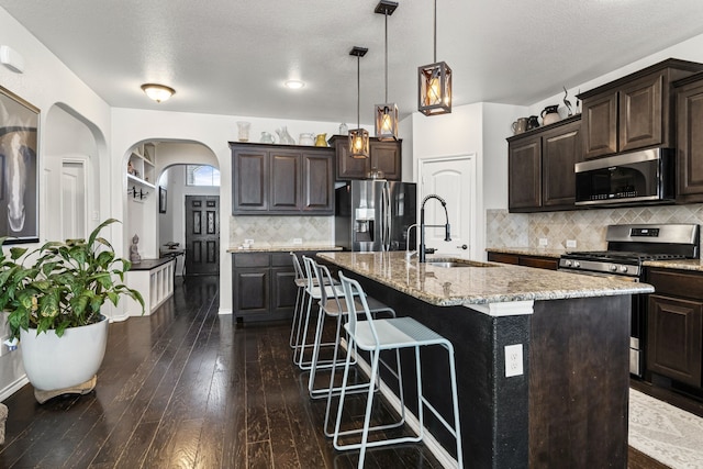 1753 Rio Penasco Rd, Fort Worth, TX 76052 - kitchen featuring stainless steel appliances, dark brown cabinetry, a kitchen breakfast bar, dark wood-style flooring, and a textured ceiling