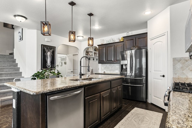 1753 Rio Penasco Rd, Fort Worth, TX 76052 - kitchen with appliances with stainless steel finishes, arched walkways, dark brown cabinets, backsplash, and an island with sink