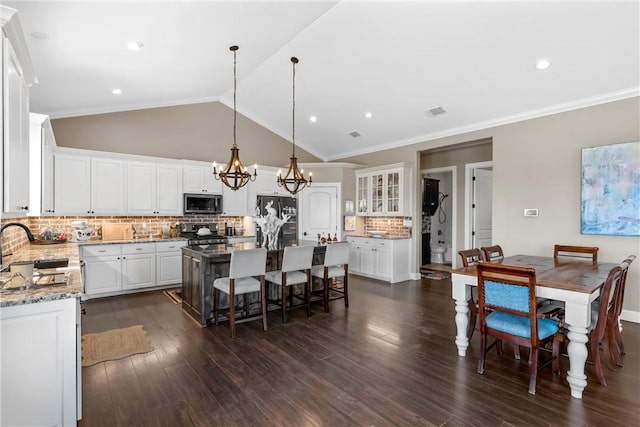 kitchen with a kitchen bar, a center island, stainless steel appliances, an inviting chandelier, and vaulted ceiling