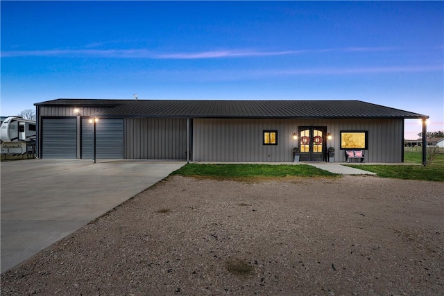view of front of property with board and batten siding, a garage, driveway, and metal roof