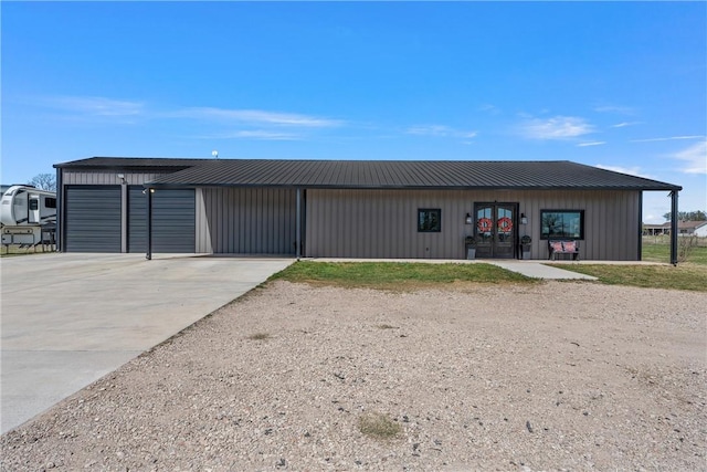 view of front of house with metal roof, a detached garage, and board and batten siding