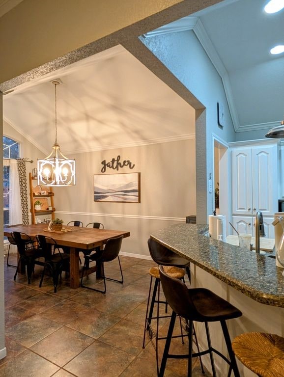 dining area with a chandelier, crown molding, baseboards, and vaulted ceiling
