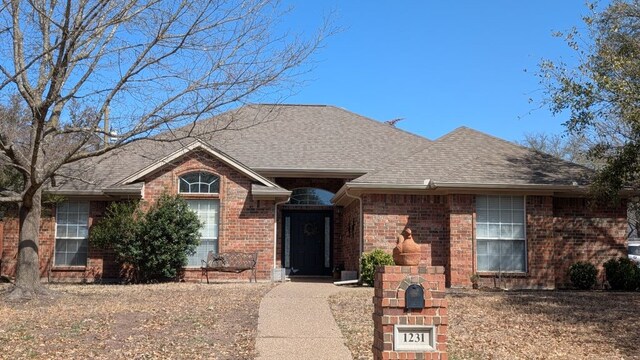 single story home with brick siding and a shingled roof