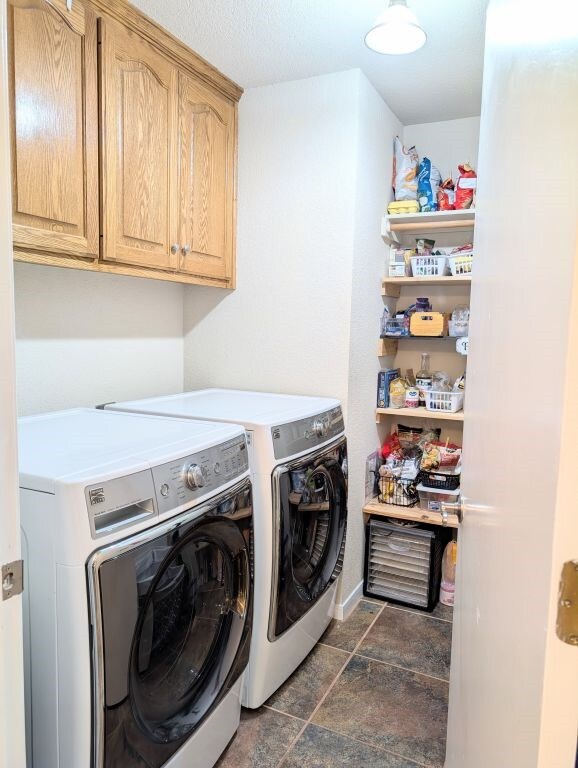 laundry area featuring stone finish flooring, cabinet space, and independent washer and dryer