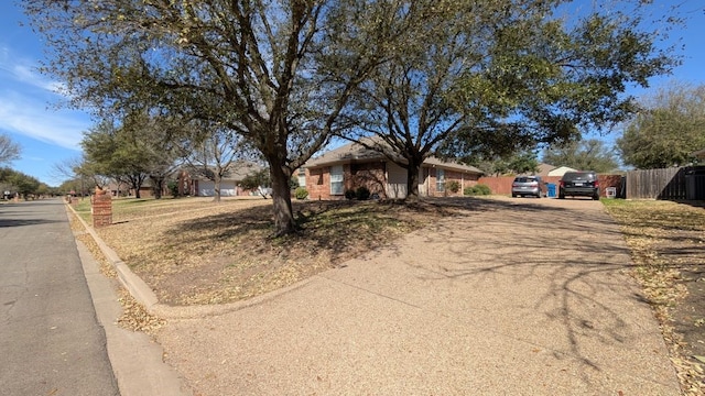 ranch-style house with driveway and fence