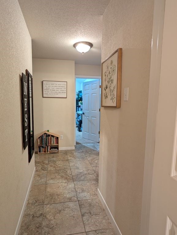 hallway with baseboards and a textured ceiling