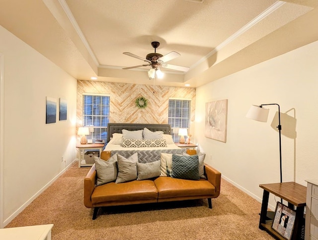 carpeted bedroom featuring ornamental molding, a tray ceiling, baseboards, ceiling fan, and an accent wall