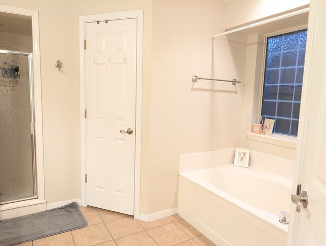 bathroom featuring baseboards, a bath, a shower stall, and tile patterned flooring