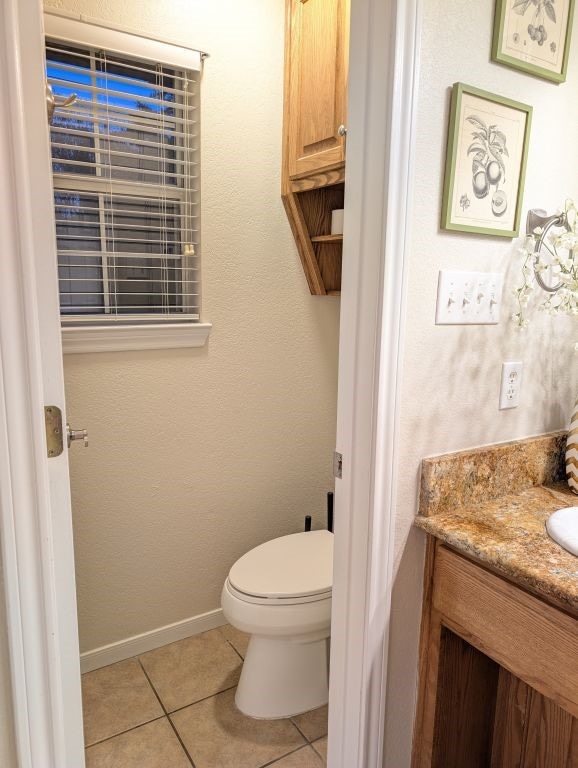 bathroom with tile patterned flooring, toilet, vanity, and baseboards