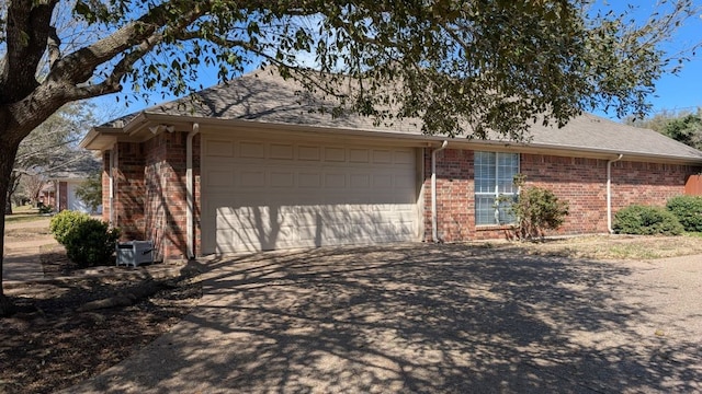 view of side of property featuring brick siding, driveway, and a garage