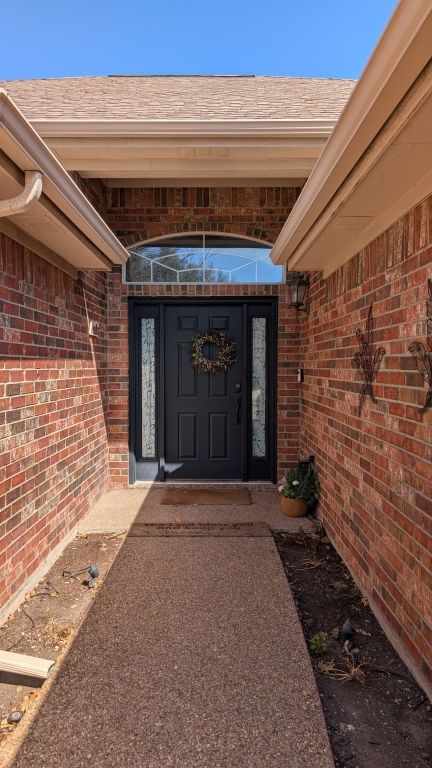 property entrance with brick siding and a shingled roof