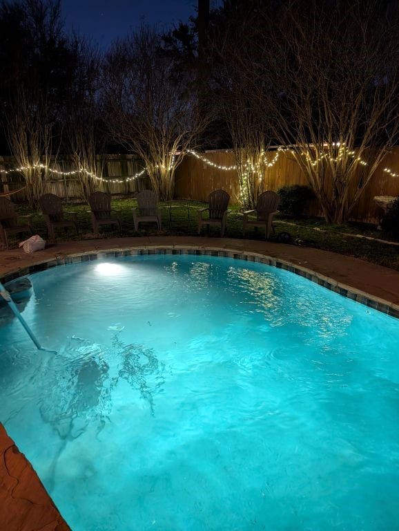 pool at twilight featuring a fenced backyard and a fenced in pool