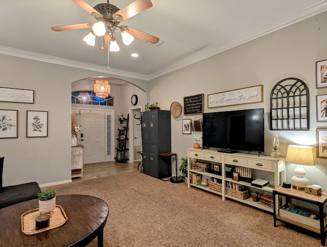 carpeted living area featuring arched walkways, baseboards, crown molding, and a ceiling fan