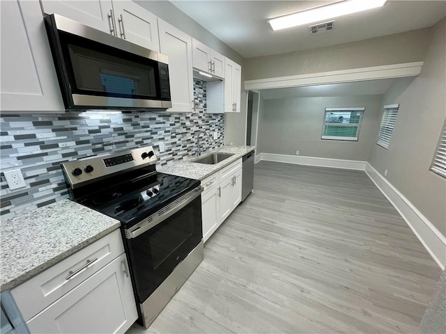 310 N Lakeview Dr, Lacy Lakeview, TX 76705 - kitchen with appliances with stainless steel finishes, a sink, light wood-type flooring, tasteful backsplash, and white cabinetry
