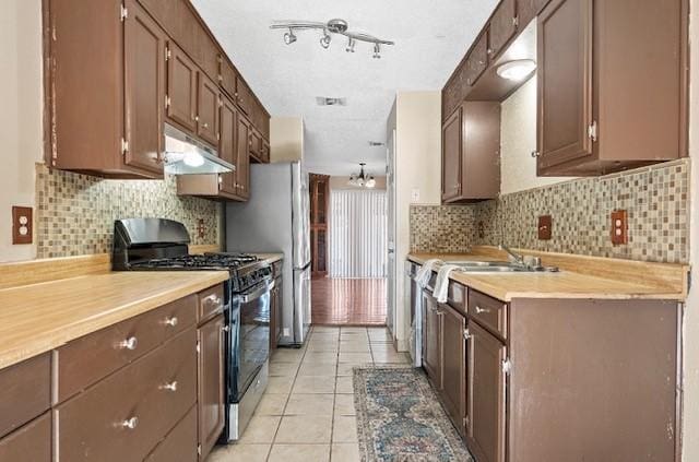 1901 Ruidoso Dr, Waco, TX 76712 - kitchen featuring appliances with stainless steel finishes, under cabinet range hood, light countertops, backsplash, and light tile patterned flooring