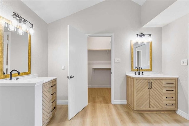 bathroom with a sink, two vanities, wood finished floors, and a spacious closet