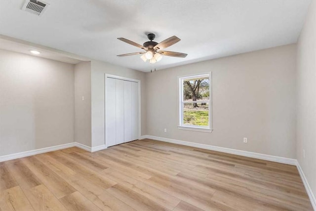 unfurnished bedroom with light wood-style flooring, baseboards, visible vents, and a closet