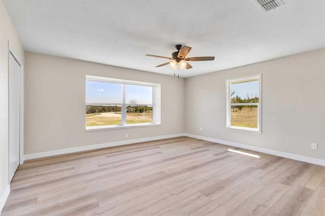 empty room with visible vents, baseboards, ceiling fan, and light wood finished floors