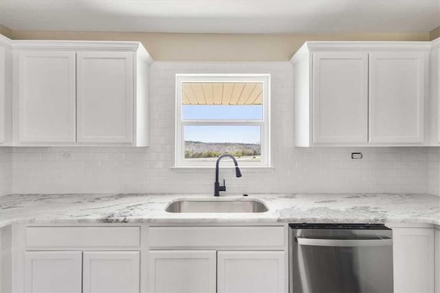 kitchen with tasteful backsplash, light stone countertops, dishwasher, white cabinets, and a sink