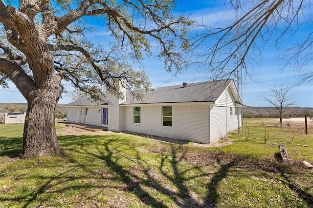 rear view of property featuring brick siding and a lawn