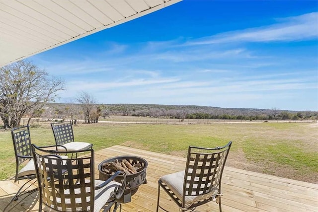 wooden terrace with a yard, a rural view, and an outdoor fire pit