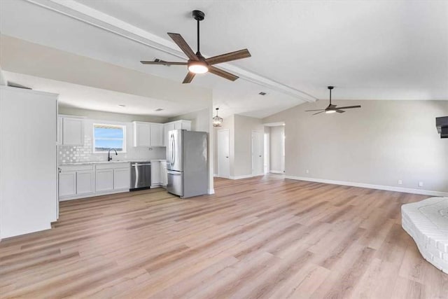 unfurnished living room with a sink, baseboards, lofted ceiling with beams, and ceiling fan