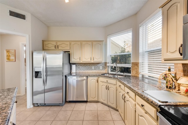 kitchen with a sink, stainless steel appliances, cream cabinets, and visible vents