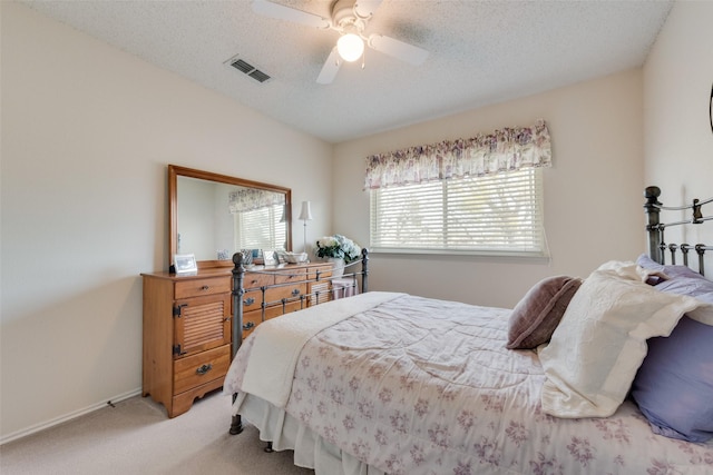 bedroom featuring visible vents, a ceiling fan, a textured ceiling, carpet floors, and baseboards
