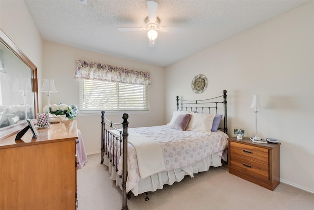 bedroom with a ceiling fan, light colored carpet, baseboards, and a textured ceiling