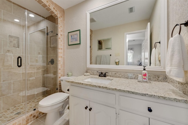 bathroom featuring visible vents, a shower stall, toilet, a textured wall, and vanity