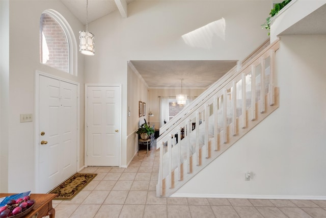 entrance foyer featuring baseboards, stairway, light tile patterned floors, a high ceiling, and a notable chandelier