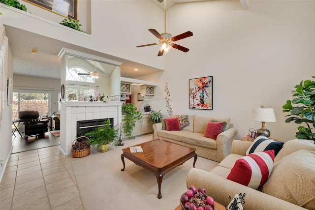 living room featuring tile patterned floors, a high ceiling, a ceiling fan, and a tile fireplace