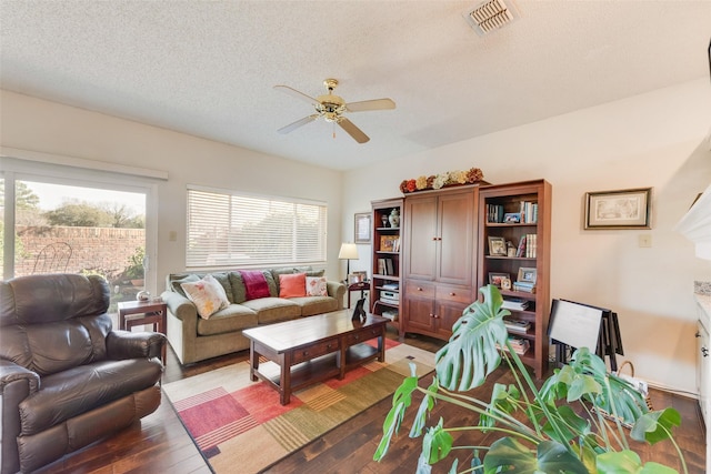 living room with visible vents, a textured ceiling, wood finished floors, and a ceiling fan