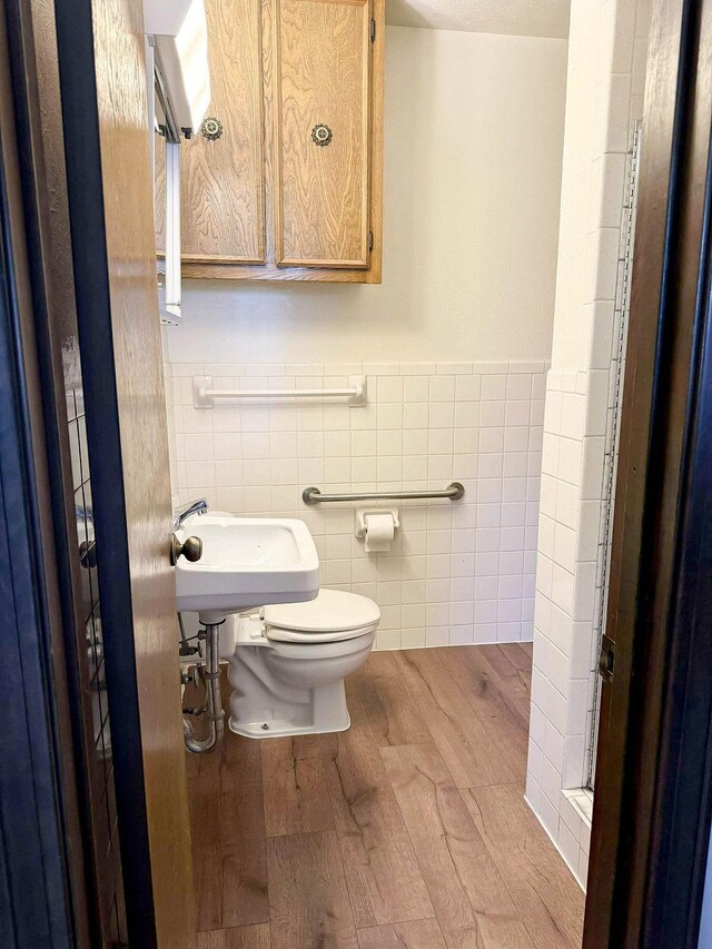 5204 Mansfield Rd, Arlington, TX 76017 - bathroom with wood finished floors, a wainscoted wall, a sink, tile walls, and toilet
