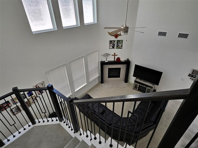 2856 Chester Dr, Celina, TX 75009 - staircase featuring a ceiling fan, a towering ceiling, a fireplace, and visible vents