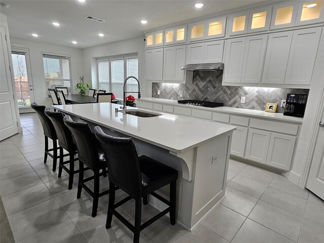 2856 Chester Dr, Celina, TX 75009 - kitchen featuring light countertops, under cabinet range hood, backsplash, a center island with sink, and a sink