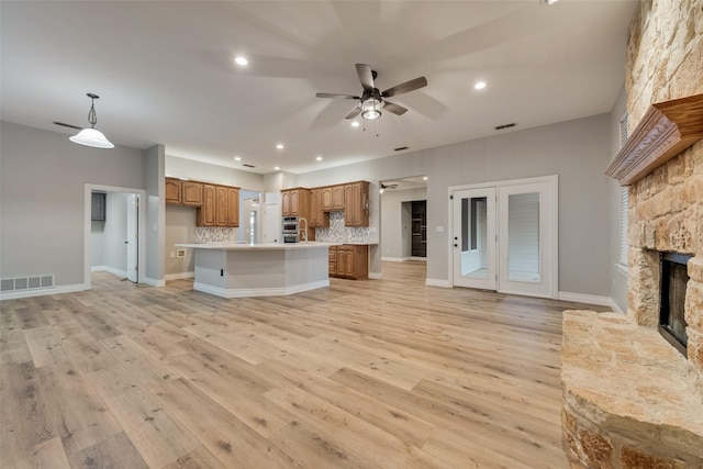 kitchen with brown cabinets, light countertops, visible vents, open floor plan, and ceiling fan
