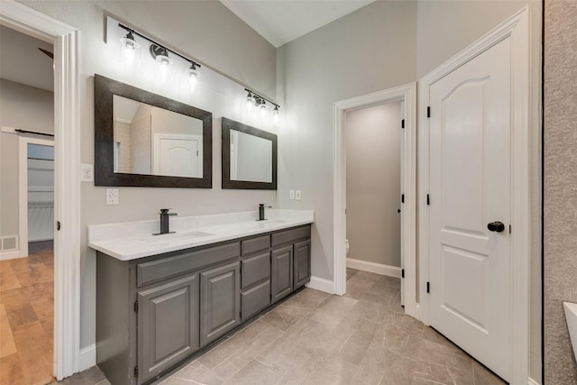 bathroom with a sink, double vanity, toilet, baseboards, and visible vents