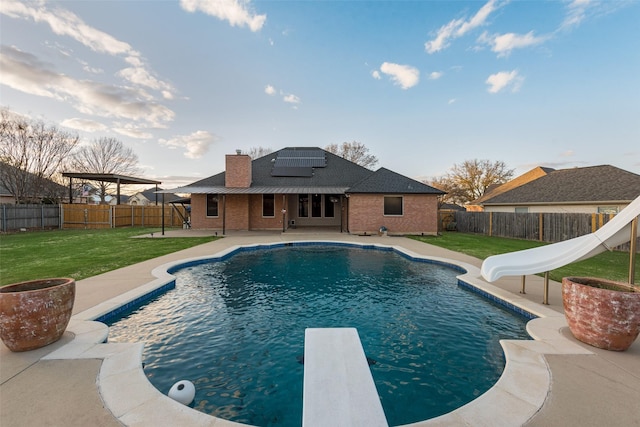 view of swimming pool featuring a water slide, a patio, a fenced backyard, and a lawn
