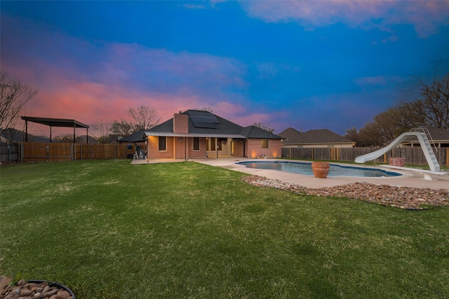 view of swimming pool with a water slide, a fenced in pool, a fenced backyard, a yard, and a patio