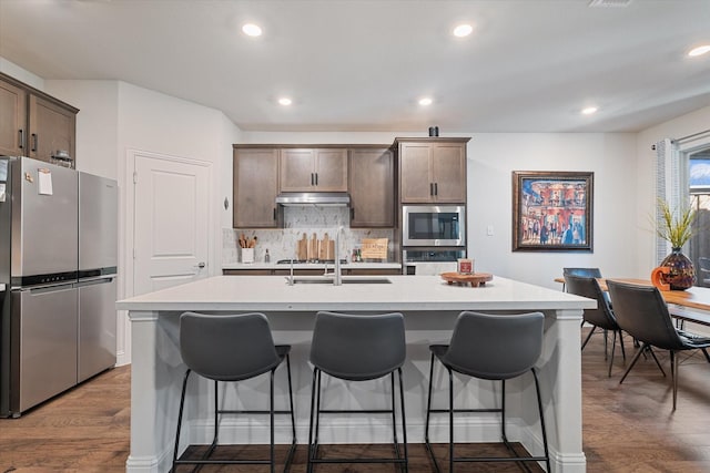 113 Glenwood Dr, Oak Point, TX 75068 - kitchen with appliances with stainless steel finishes, under cabinet range hood, a center island with sink, a kitchen bar, and light countertops
