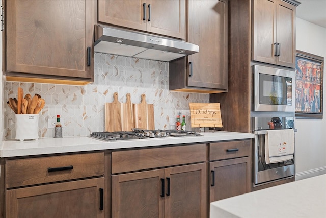113 Glenwood Dr, Oak Point, TX 75068 - kitchen with under cabinet range hood, appliances with stainless steel finishes, tasteful backsplash, and light countertops
