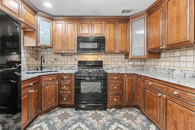 4512 Fletcher Ave, Fort Worth, TX 76107 - kitchen featuring brown cabinetry, visible vents, a sink, black appliances, and tasteful backsplash