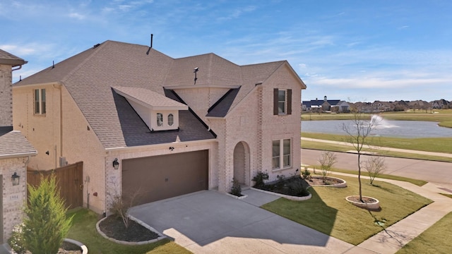 view of front of house with a front lawn, a garage, a water view, driveway, and brick siding